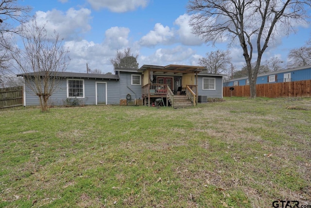 rear view of house featuring central AC, fence, and a lawn