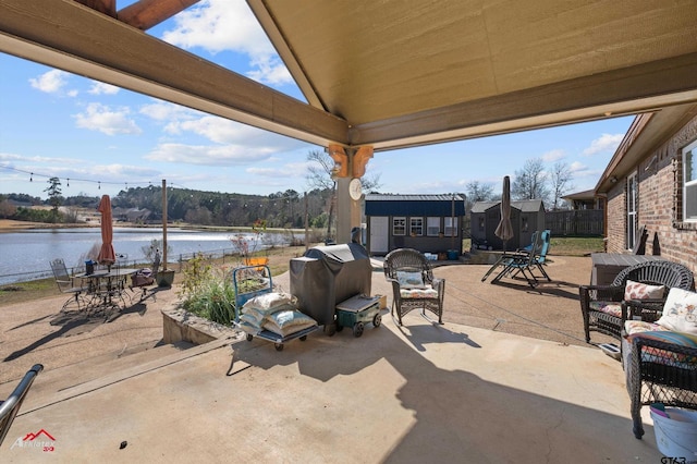 view of patio / terrace featuring a water view, a grill, and an outdoor structure