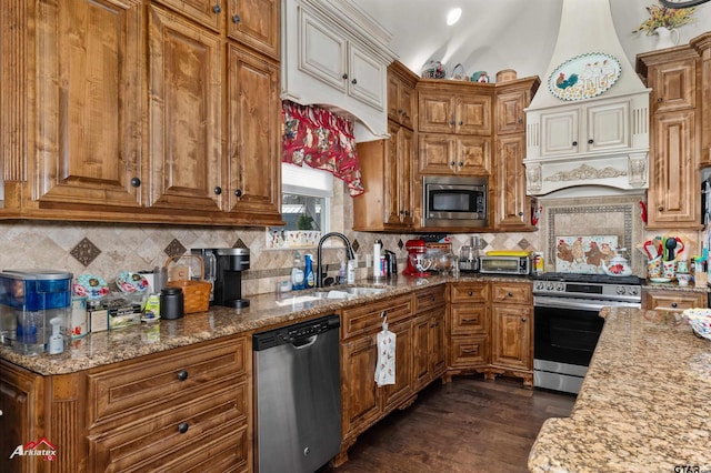 kitchen with lofted ceiling, appliances with stainless steel finishes, light stone counters, and tasteful backsplash