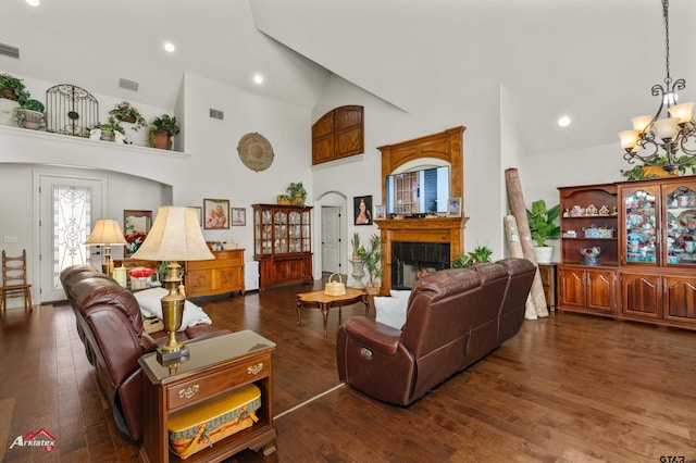 living room featuring a notable chandelier, high vaulted ceiling, dark wood-type flooring, and a tiled fireplace