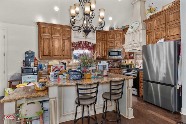 kitchen with a center island, appliances with stainless steel finishes, a kitchen breakfast bar, and dark stone counters