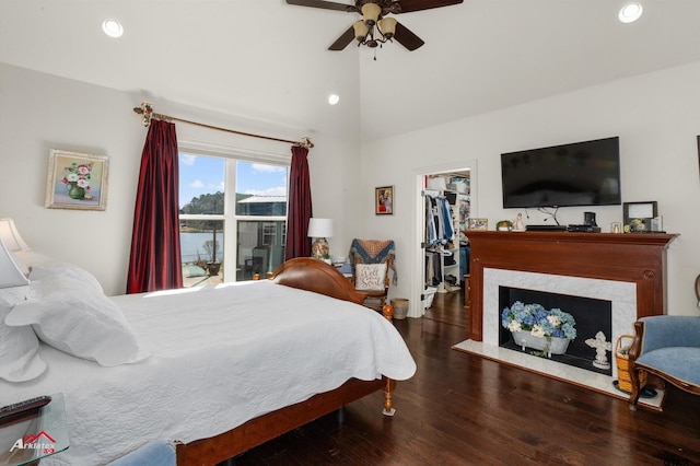 bedroom featuring a fireplace, lofted ceiling, a walk in closet, ceiling fan, and dark hardwood / wood-style floors