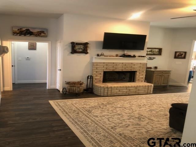 living room with dark wood-type flooring, a fireplace, and ceiling fan