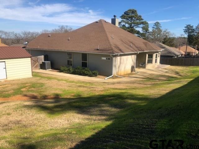 rear view of property with central AC unit, a yard, and a storage shed