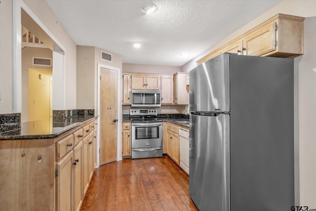 141 Green Mesa Ln, Holly Lake Ranch, TX 75765 - kitchen with stainless steel appliances, light brown cabinets, dark wood-style floors, a textured ceiling, and dark stone countertops