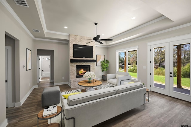 living room with a tray ceiling, ceiling fan, dark hardwood / wood-style floors, and ornamental molding