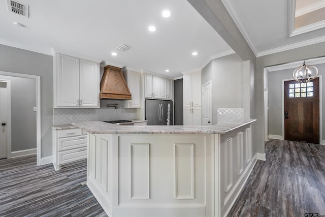 kitchen with appliances with stainless steel finishes, ornamental molding, custom exhaust hood, white cabinets, and dark hardwood / wood-style flooring