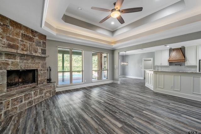 unfurnished living room with ceiling fan, crown molding, dark hardwood / wood-style floors, and a raised ceiling