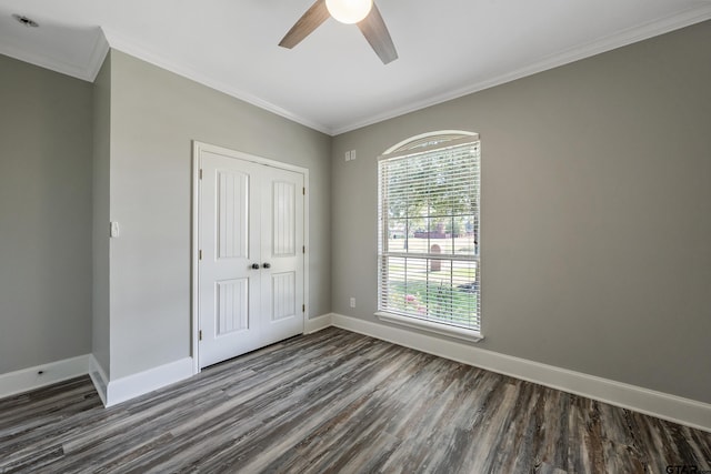 unfurnished bedroom with ornamental molding, dark hardwood / wood-style flooring, ceiling fan, and a closet