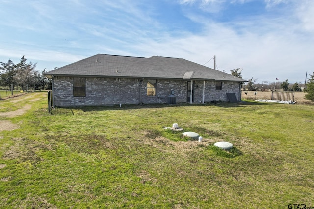 rear view of house featuring cooling unit and a lawn