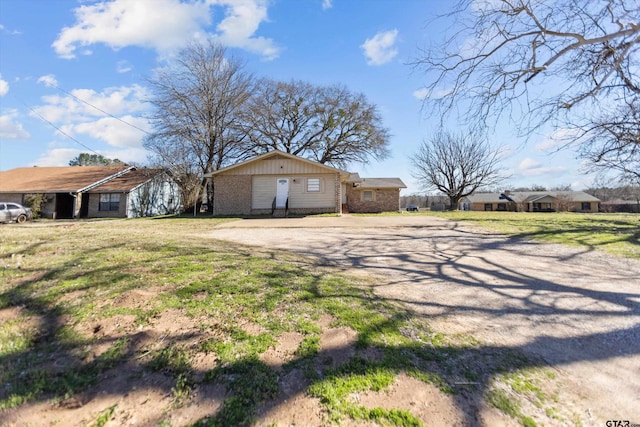 view of home's exterior featuring brick siding, a yard, and dirt driveway