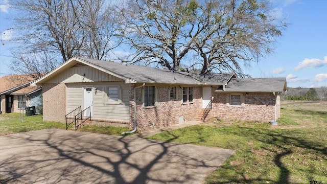 view of front facade with entry steps, brick siding, and a front lawn