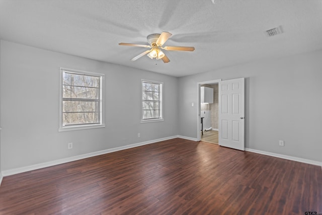 unfurnished room with a textured ceiling, wood finished floors, a ceiling fan, visible vents, and baseboards