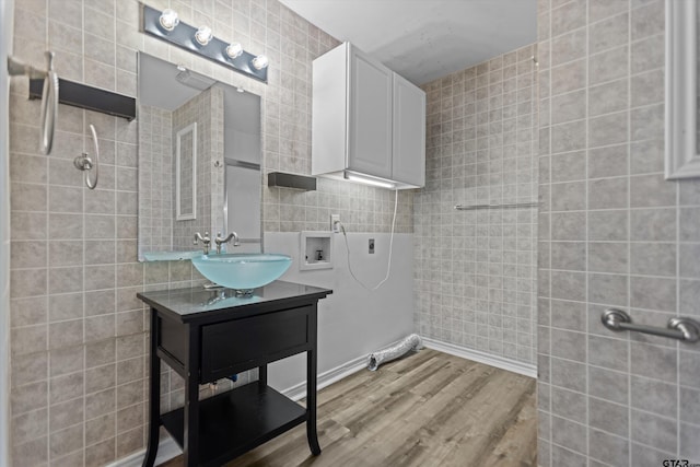 full bath with wood finished floors, a tile shower, and tile walls