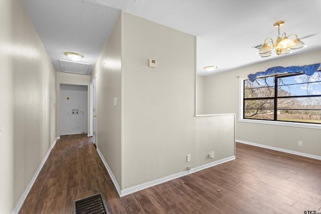 hall with attic access, visible vents, baseboards, and wood finished floors