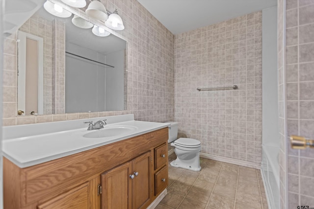 bathroom with toilet, tile patterned flooring, tile walls, and vanity