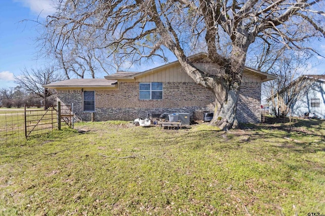 exterior space featuring brick siding, a lawn, and fence