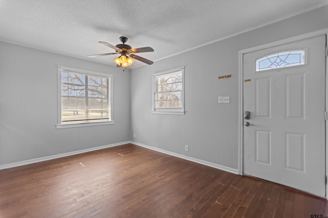 foyer entrance featuring dark wood-style floors, crown molding, a textured ceiling, and baseboards