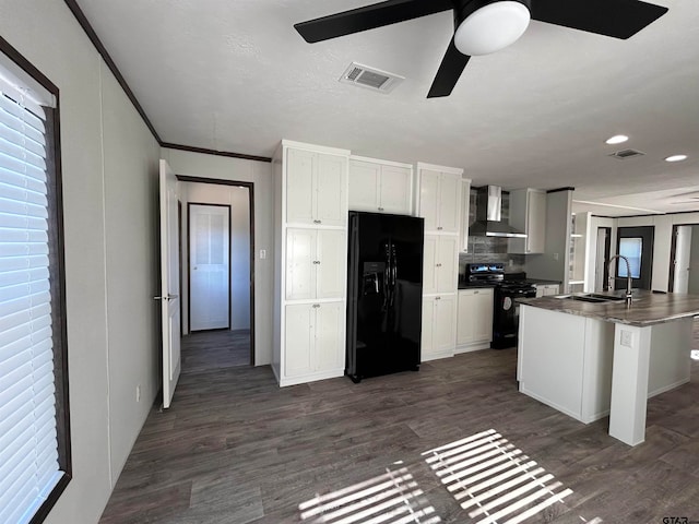 kitchen featuring dark wood-type flooring, sink, black appliances, and wall chimney range hood