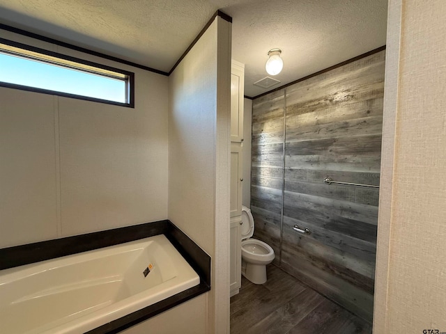 bathroom featuring a washtub, a textured ceiling, toilet, hardwood / wood-style flooring, and ornamental molding