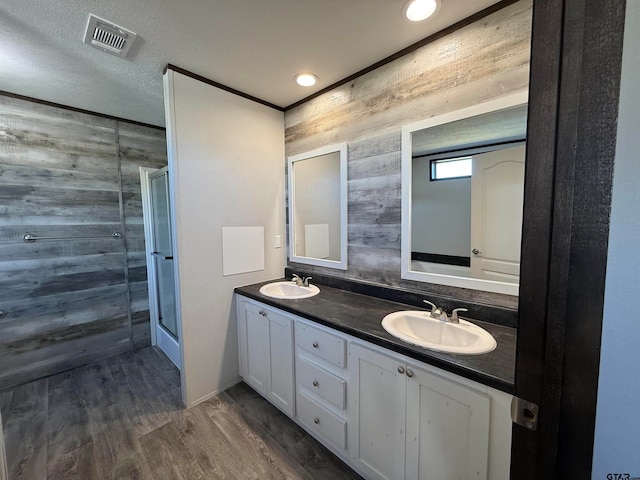 bathroom featuring vanity, hardwood / wood-style flooring, a shower with shower door, and wood walls