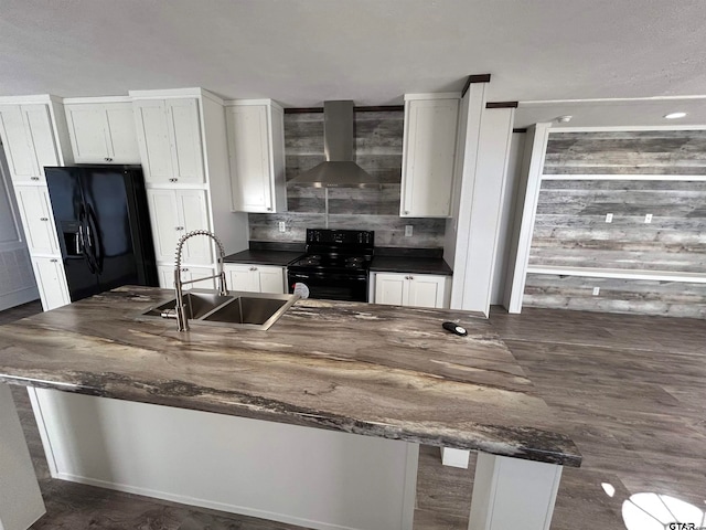 kitchen with wall chimney range hood, dark hardwood / wood-style flooring, white cabinets, and black appliances