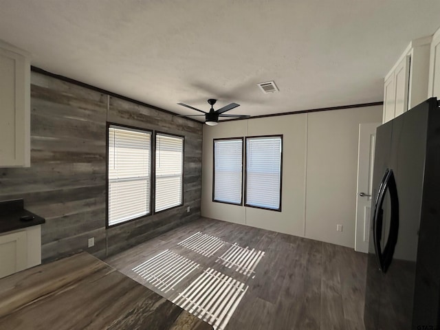 kitchen with refrigerator, ceiling fan, wooden walls, dark wood-type flooring, and white cabinets