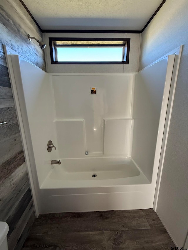 bathroom featuring hardwood / wood-style floors, a healthy amount of sunlight, shower / tub combination, and a textured ceiling