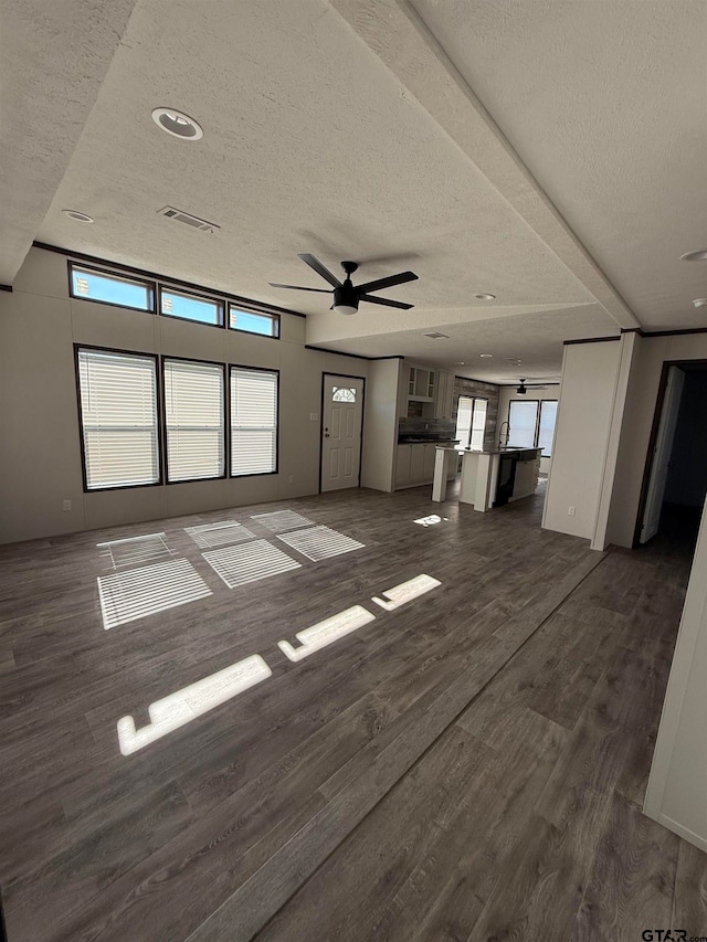 unfurnished living room featuring a textured ceiling, ceiling fan, and dark hardwood / wood-style floors