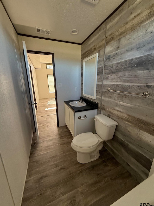 bathroom featuring hardwood / wood-style flooring, vanity, and wood walls