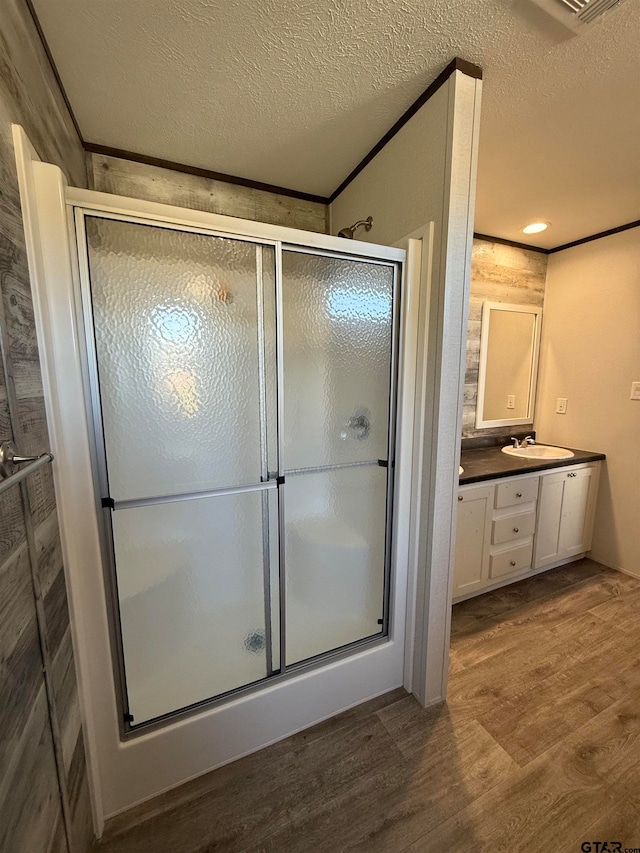 bathroom with vanity, a shower with shower door, wood-type flooring, and a textured ceiling