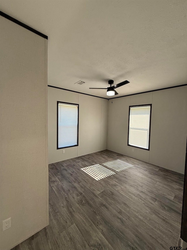 unfurnished room featuring a textured ceiling, ceiling fan, and dark wood-type flooring