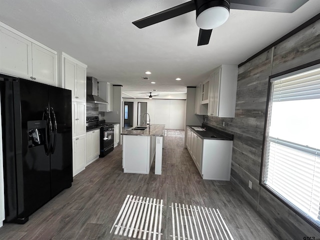 kitchen with dark hardwood / wood-style flooring, wall chimney range hood, sink, black appliances, and a kitchen island