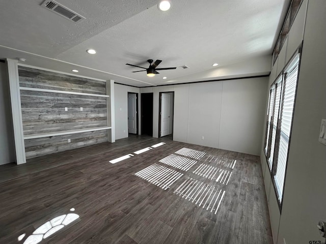 interior space featuring a textured ceiling, ceiling fan, wood walls, and dark hardwood / wood-style floors