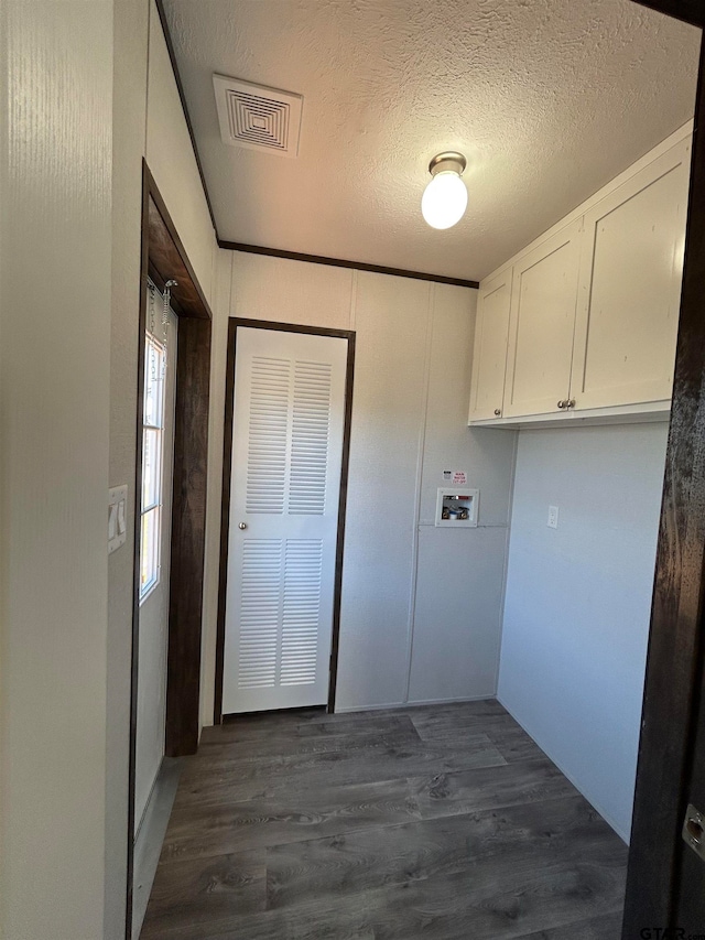 clothes washing area featuring cabinets, a textured ceiling, dark hardwood / wood-style flooring, and hookup for a washing machine