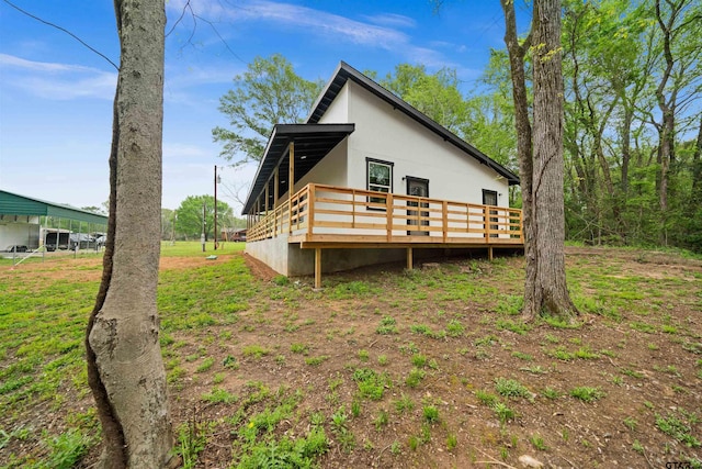 back of house featuring stucco siding and a deck