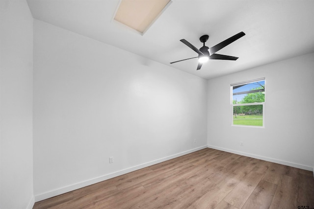 spare room with attic access, baseboards, light wood-style floors, and ceiling fan