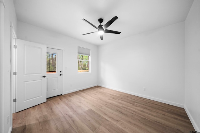 empty room with baseboards, ceiling fan, and light wood-style floors