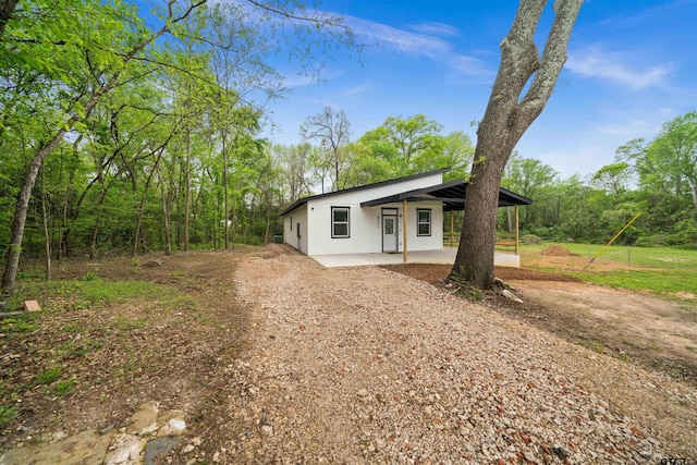 view of front of house with driveway, stucco siding, and a patio area