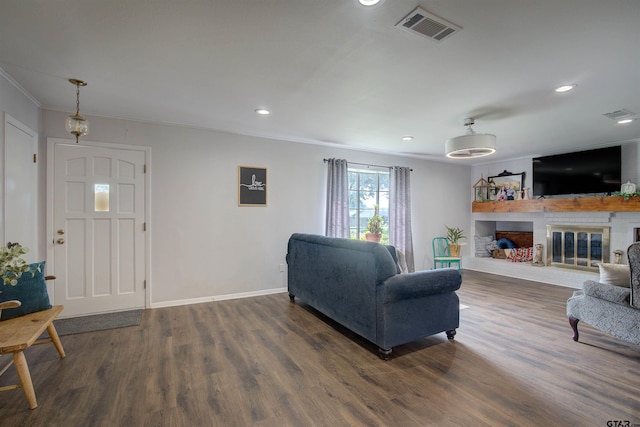 living room with crown molding, dark hardwood / wood-style flooring, and a brick fireplace