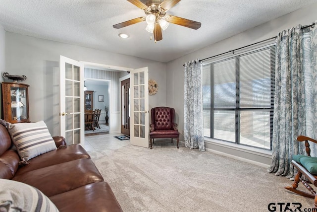 sitting room with light carpet, ceiling fan, french doors, and a textured ceiling