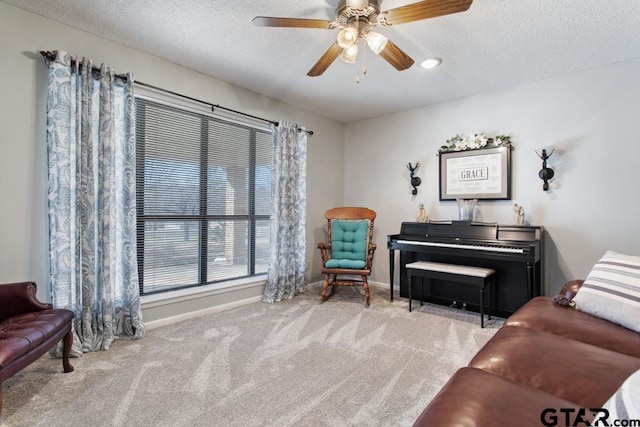 sitting room featuring ceiling fan, light carpet, and a textured ceiling