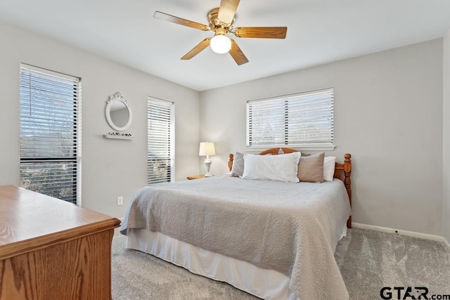 carpeted bedroom featuring multiple windows and ceiling fan