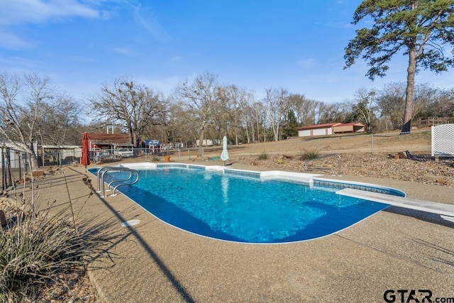 view of pool with a patio area and a diving board