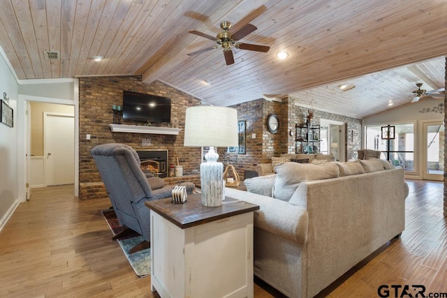 living room featuring vaulted ceiling with beams, light hardwood / wood-style flooring, ceiling fan, brick wall, and a fireplace