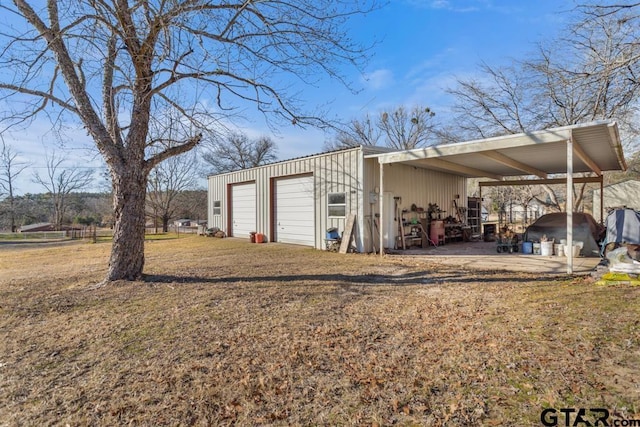 view of outdoor structure featuring a garage, a carport, and a lawn