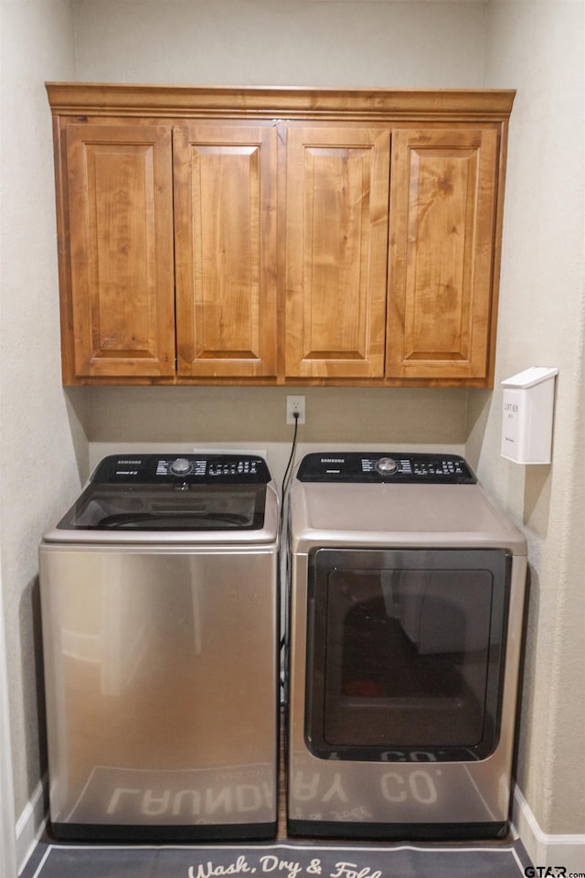 washroom with baseboards, washer and dryer, and cabinet space