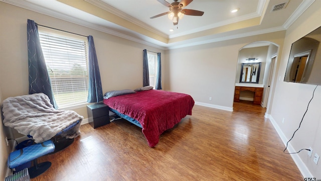 bedroom featuring a raised ceiling, wood finished floors, visible vents, ornamental molding, and baseboards