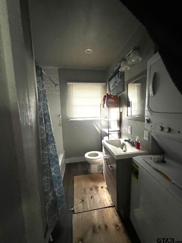 bathroom with plenty of natural light, vanity, stacked washer / dryer, and toilet