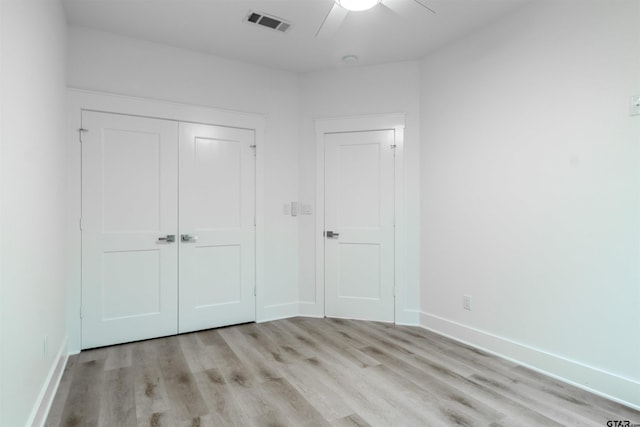 unfurnished bedroom with ceiling fan, a closet, and light wood-type flooring